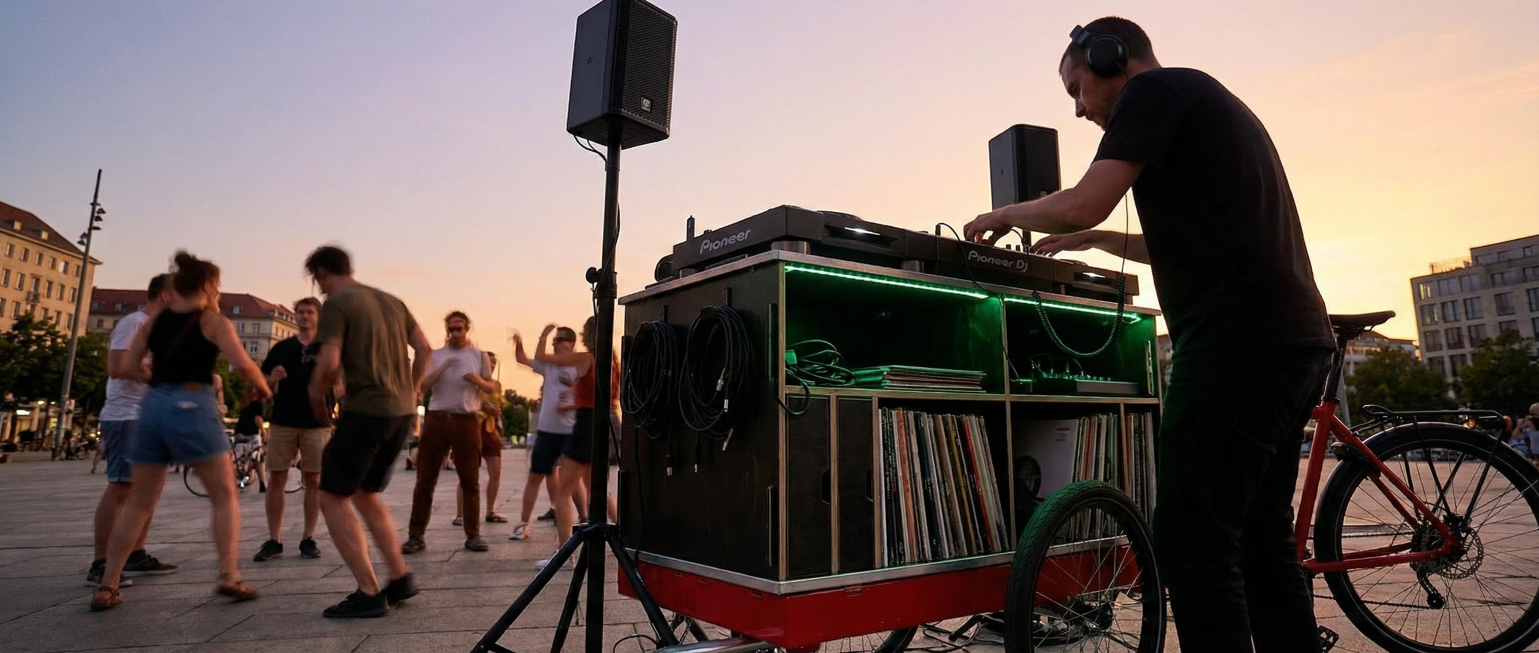 Mobile DJ booth and sound system on a modular bike trailer at an evening block party
